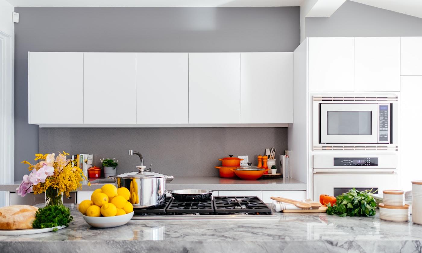 A bright white kitchen with a marble island and lemons on the counter