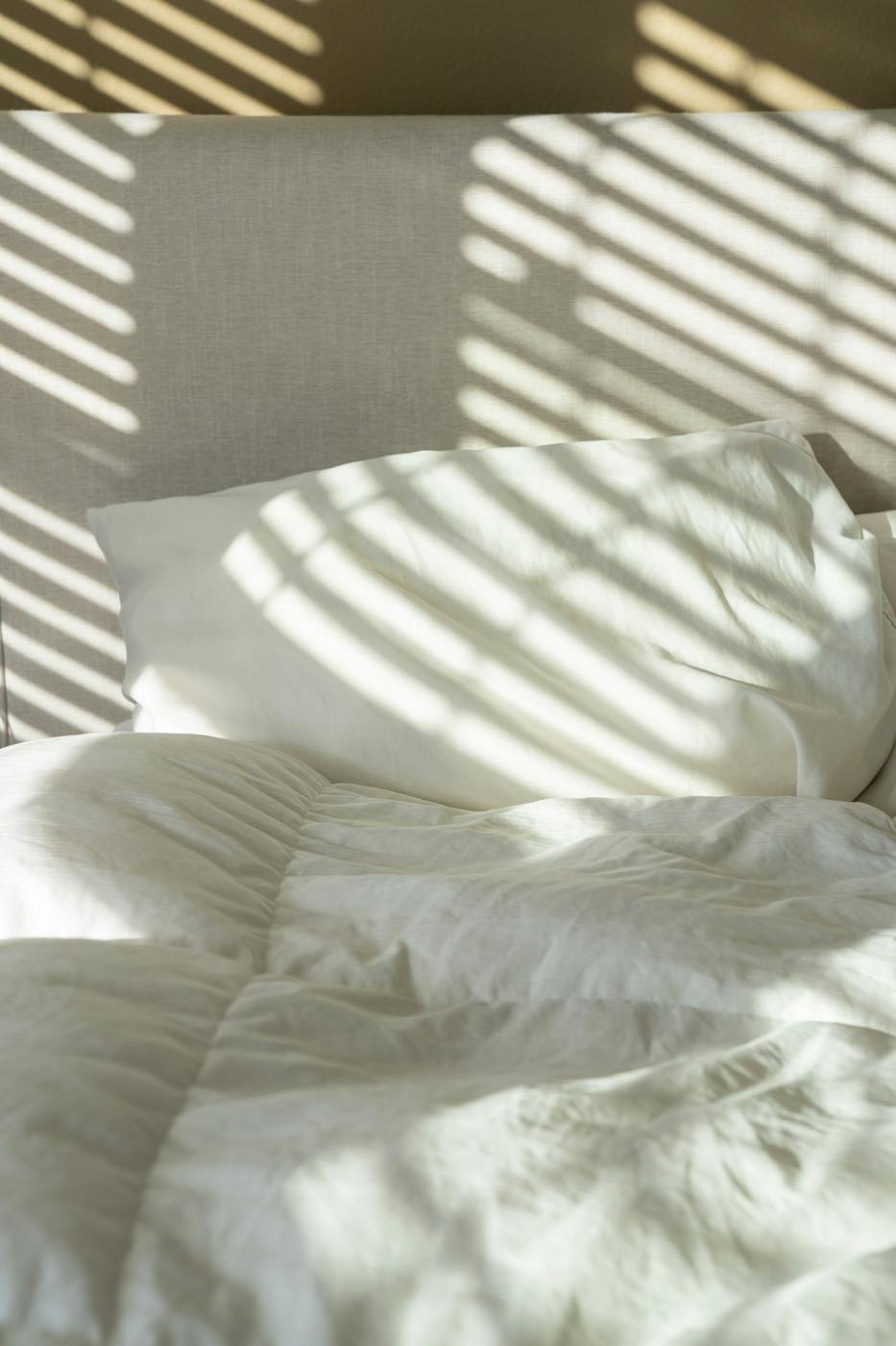 Morning light across freshly made white bed linen